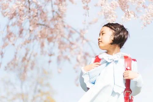 桜の木の下のランドセルを背負った女の子